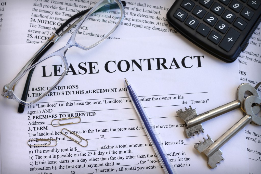 image of lease contract covered with paperclips, calculator, glasses, and keys
